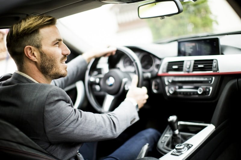 A young, attractive male that is driving a car.