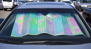 View of a silver car that has a sun shade inside covering the dash and interior of the car.