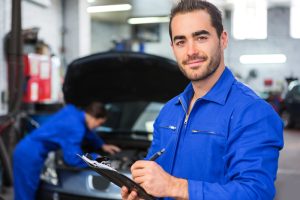 A professional worker in a body shop with a man in the background doing car service work.