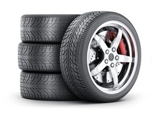 Three tires stacked on top of one another with a fourth leaned up against the tires.