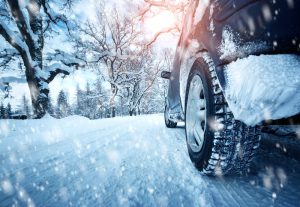 A view from the road of a car driving in the snow with snow tires.