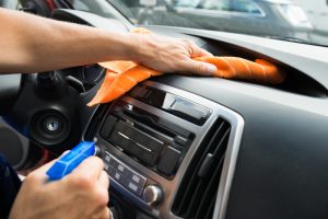 A person that is cleaning the dashboard of their car. 