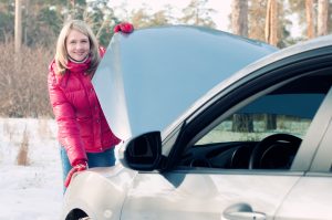 Smiling caucasian woman standing by her car with bonnet opened