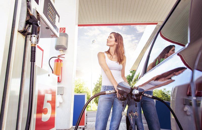 A woman filling her car up with gas. 
