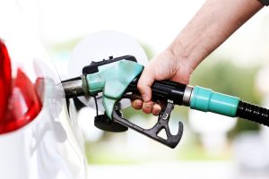 A close-up view of a person filling up their car. Only the had is visible with the gasoline pump.