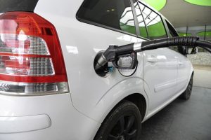 A white natural gas vehicle that is being filled up with fuel.
