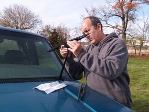 A man that is putting on new windshield wiper blades.