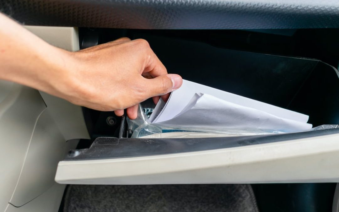 hand stirring papers in a glove box (dashboard)