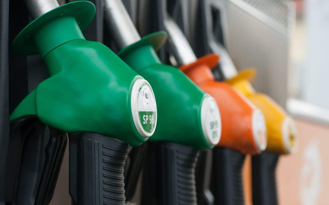 A close-up, selective focus view of various colorful fuel nozzles lined up at a gas station pump, highlighting fuel choice options and regular fuel system maintenance services offered by Scott's Auto.