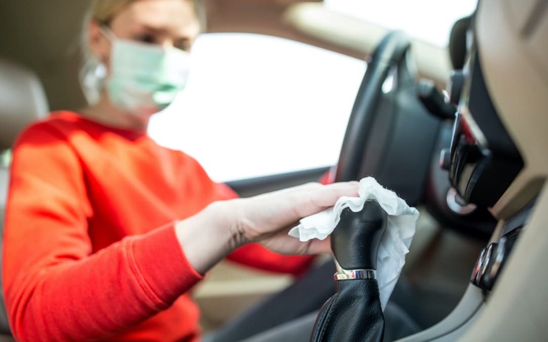 Epidemic outbreak. Woman cleaning steering wheel in the car.