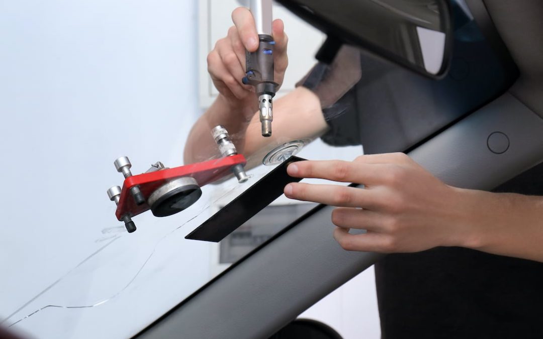 Specialist fixing crack on car windshield in repair shop