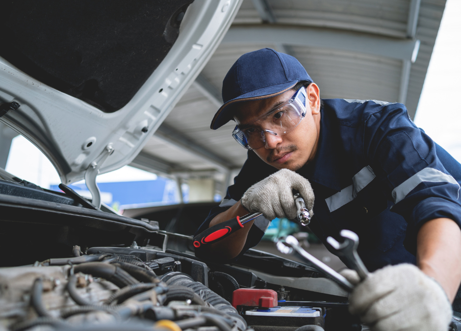 mechanic working under hood of a car