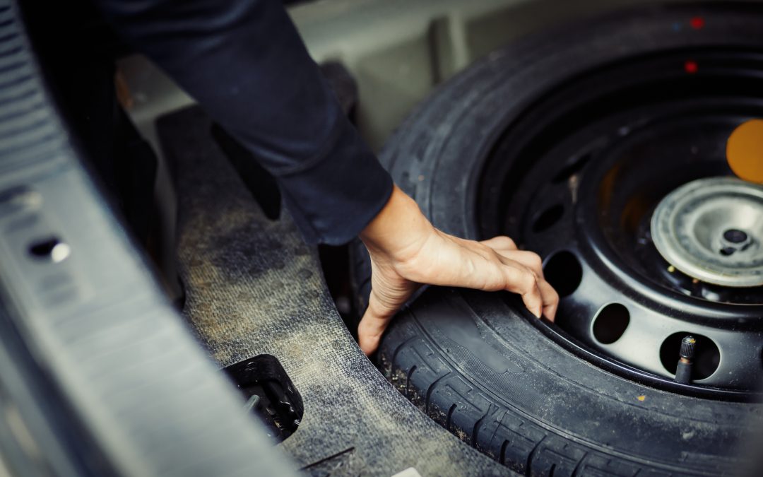 Close up mechanic hand taking spare tire at boot