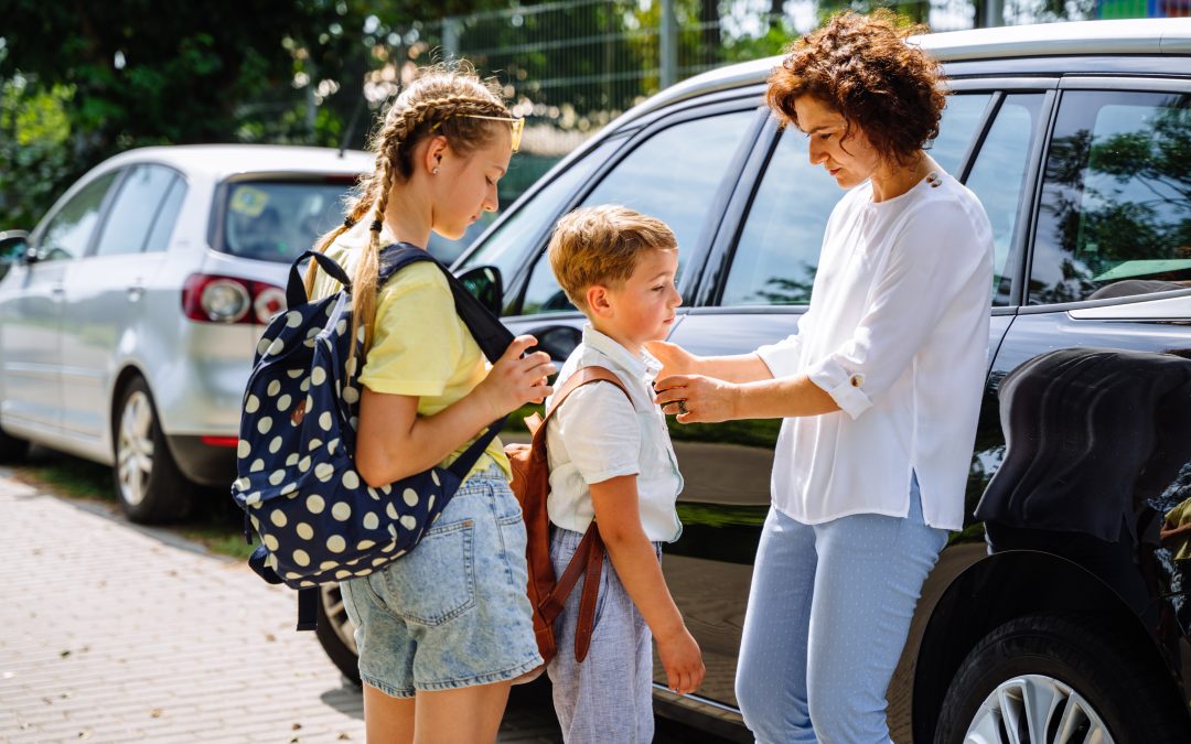 Single mother saying goodbye to her two children at ar parking outdoor, near school. Single mom, school, family, education outdoor concept.