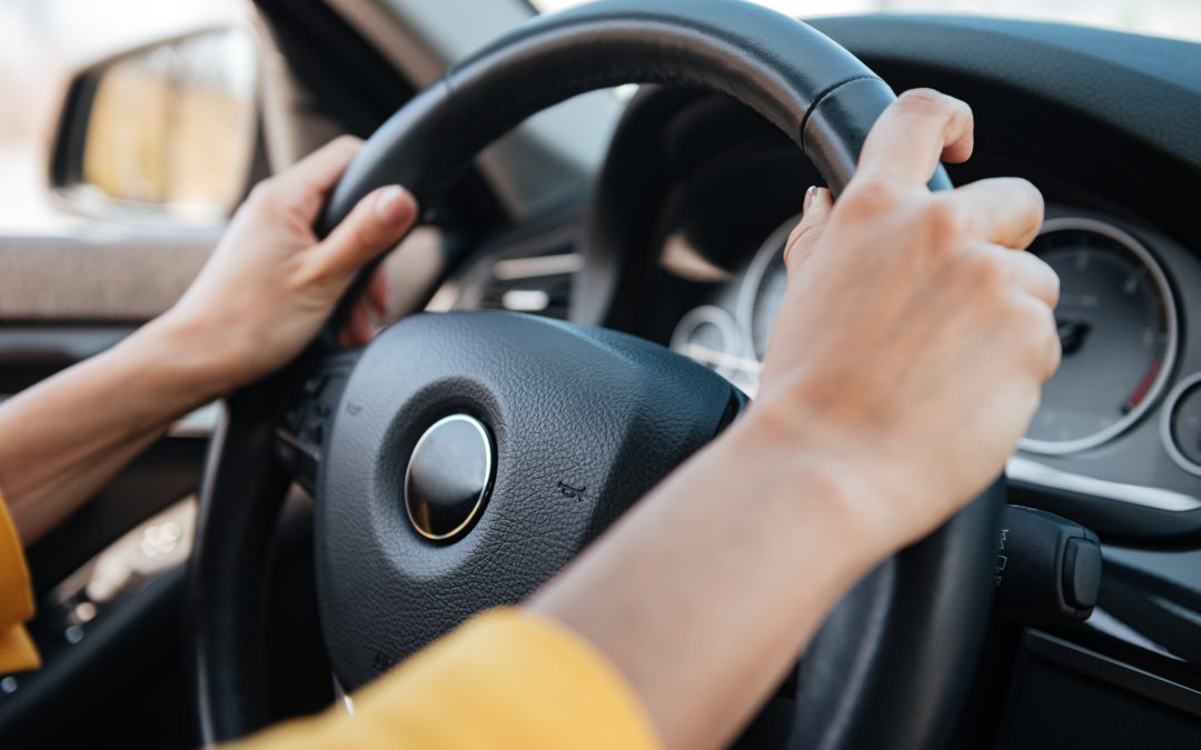 Female hands on steering wheel while driving a car